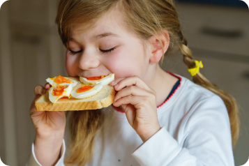 Child eating eggs on toast