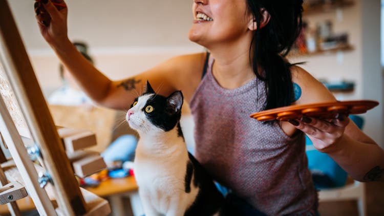 Woman painting with a cat on her lap