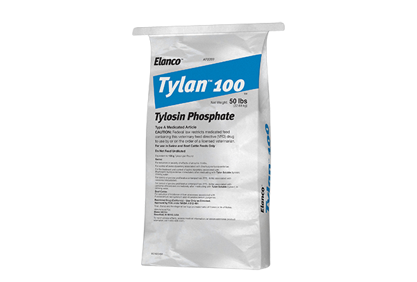 A large white 50 lb bag of Elanco Tylan 100 (Tylosin Phosphate) Type A Medicated Article, featuring a slanted blue block with the product name in white text.
