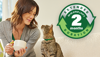 A woman looking at her tabby cat with an icon that reads extended duration each dose lasts 2 months