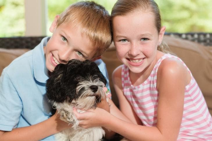 A young girl and boy cuddling with their new puppy